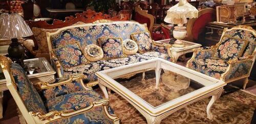 luxury living room set that includes a cabriole sofa and 2 armchairs with blue brocade silk cushions and matching pillows. Carved wood trim is painted in a cream color with gold gilding. Matching glass topped wood coffee table to complete the baroque styl