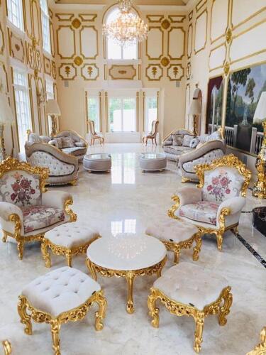 elegant gilded floral arm chairs with matching tufted footstools and coffee table. Elegant long curved sofas with gilded trim and tufted cushion backs with matching pillows and coffee tables. Matching gilded side chairs in bay window nook. Luxury Italian 